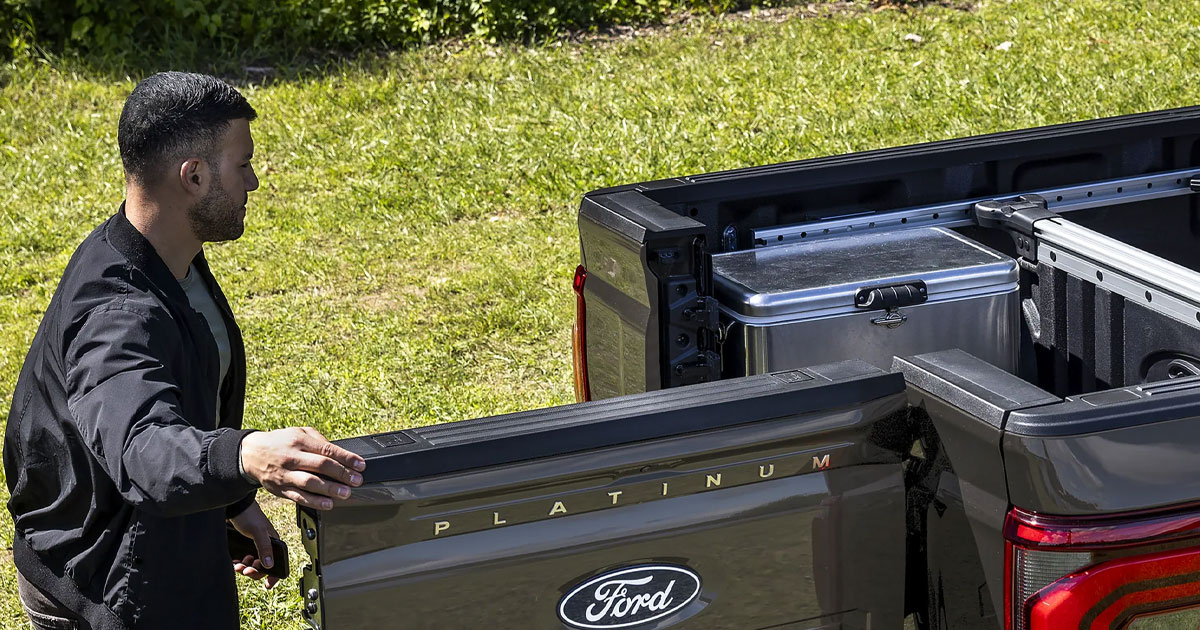 A guy opening the door to the bed of a Ford F-150 truck.