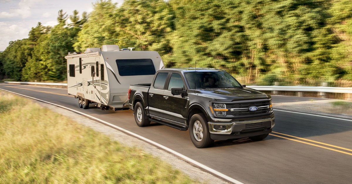 A Ford F-150 hauls an RV trailer on an open road.